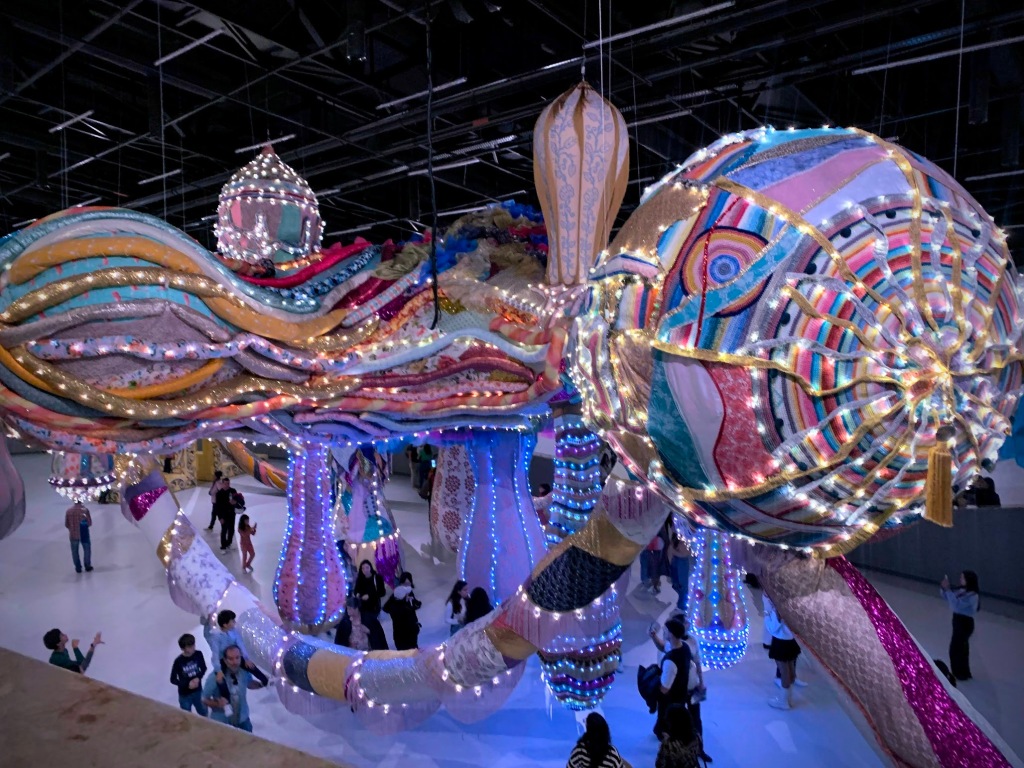 A modern art museum exhibit of a fish made of fabric and lights. 