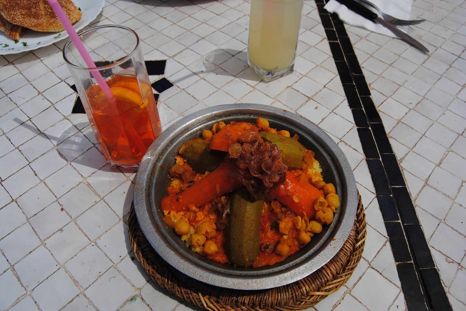 A half-drunk Aperol Spritz and a plate of vegetable tagine
