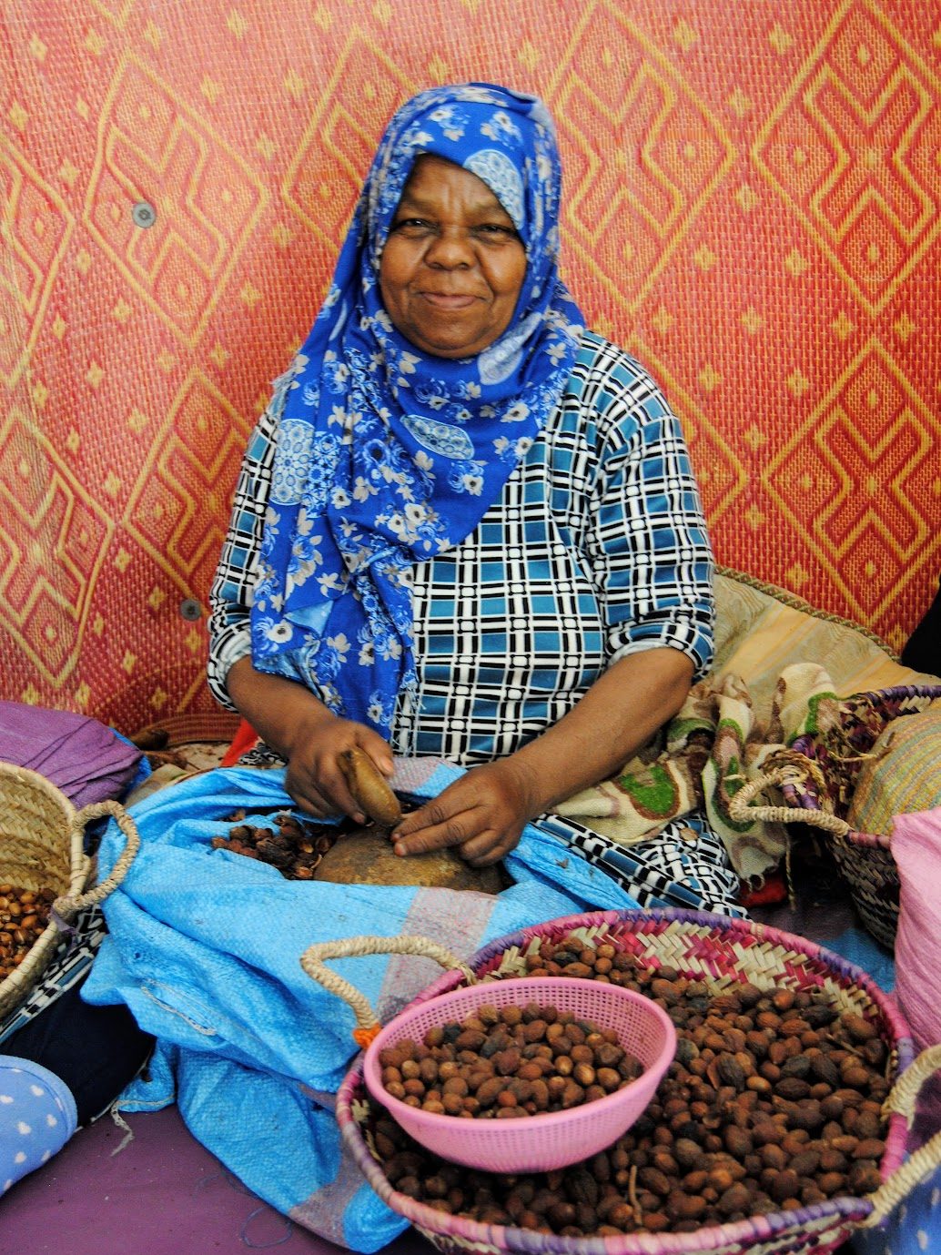 A woman in a blue hijab sitting and making argan oil
