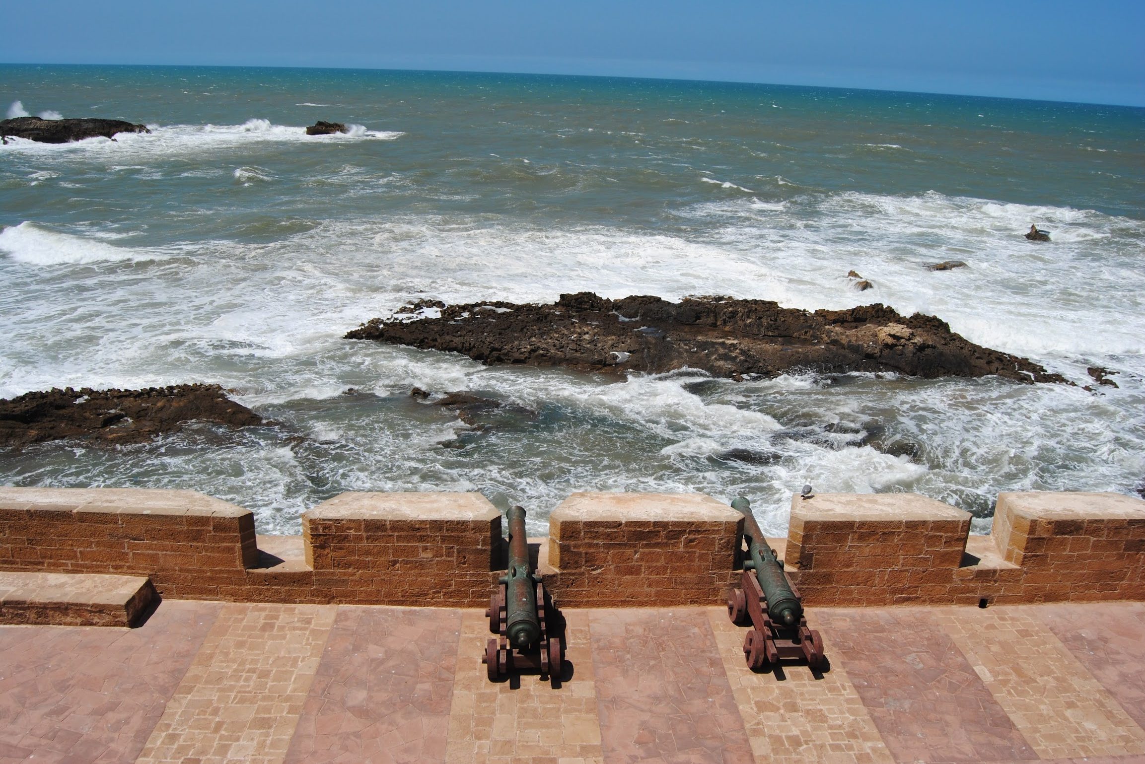 Canons on a city wall pointing towards the ocean